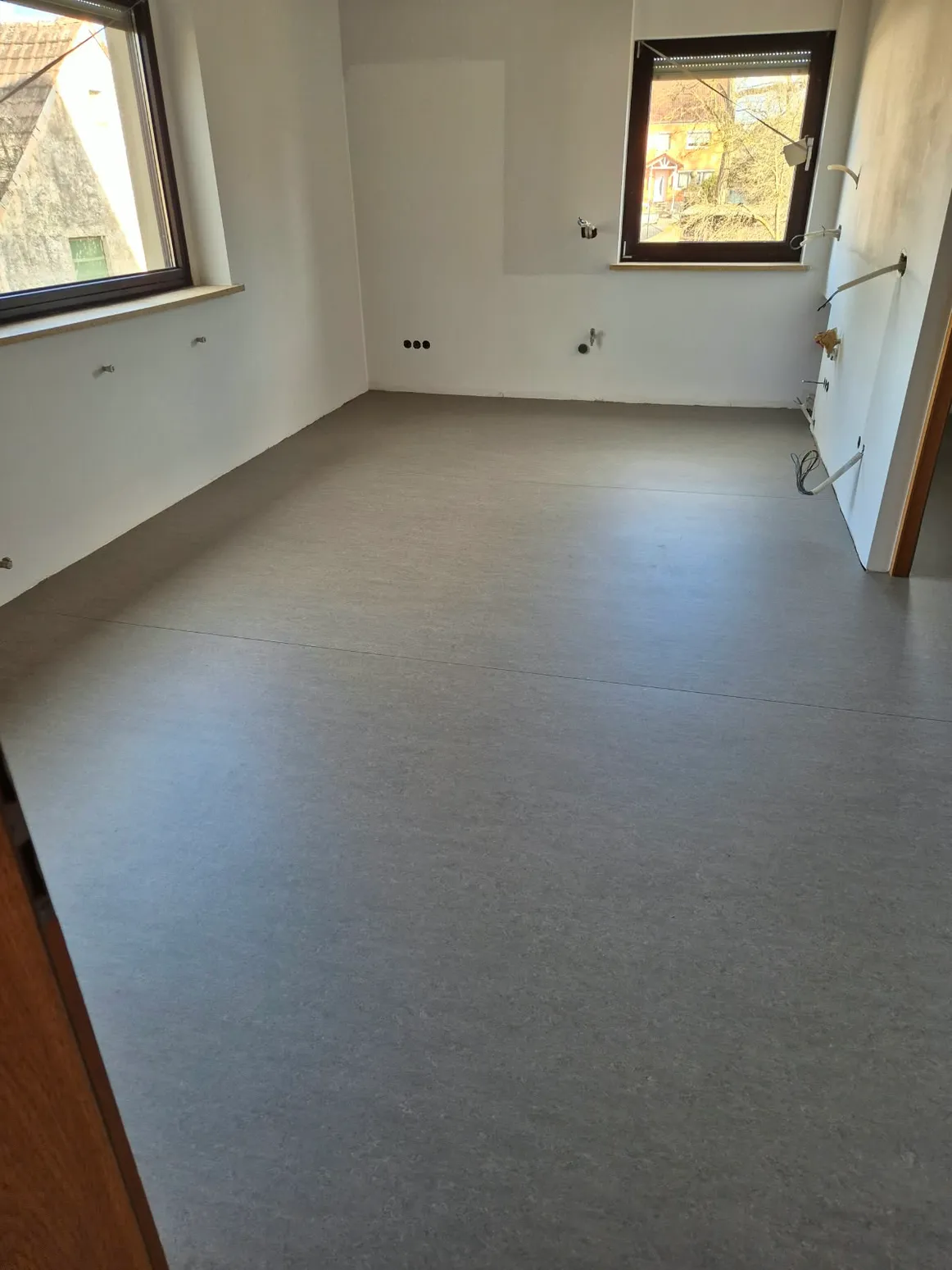 Vinyl Designboden hellgrau verlegt Neu verlegter hellgrauer Vinyl-Designboden in leerem Raum mit zwei Fenstern