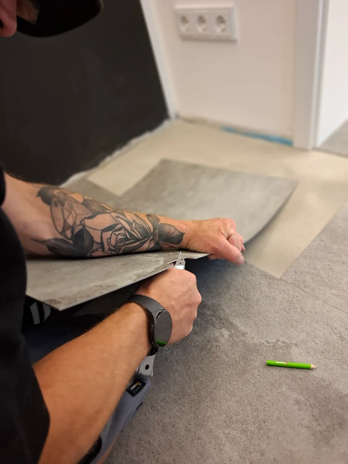 Designbelag verlegen Handwerker Handwerker legt eine Designbelag-Fliese auf dem vorbereiteten Untergrund aus