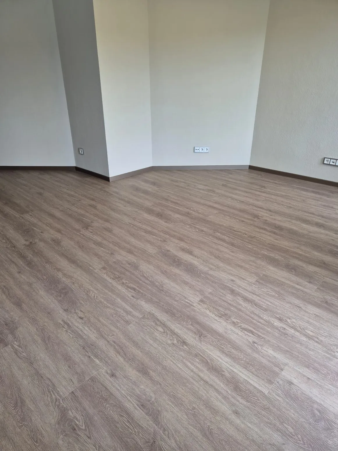 Vinyl-Designboden in grau-brauner Holzoptik in leerem Raum